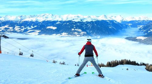 Rear view of man skiing on snowcapped mountain against sky