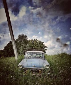 Abandoned car on field against sky