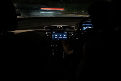 Rear view of man driving car in illuminated city