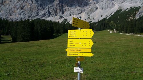 Sign board on grassy field against mountain