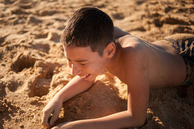 High angle view of shirtless boy on sand at beach