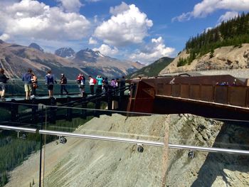 Group of people walking on road against mountain range