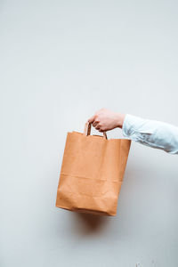 Vertical view of the unknown millennial woman holding paper bag with takeaway food