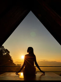 Rear view of silhouette woman standing against sky during sunset