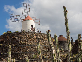 Low angle view of traditional windmill on field against sky