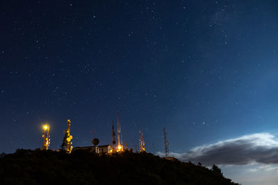 Low angle view of illuminated clock tower against sky at night