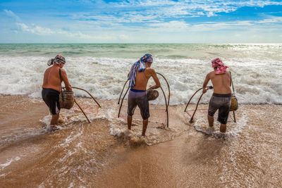 Men fishing in sea against sky