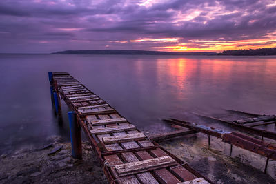 Pier over lake against sky during sunset