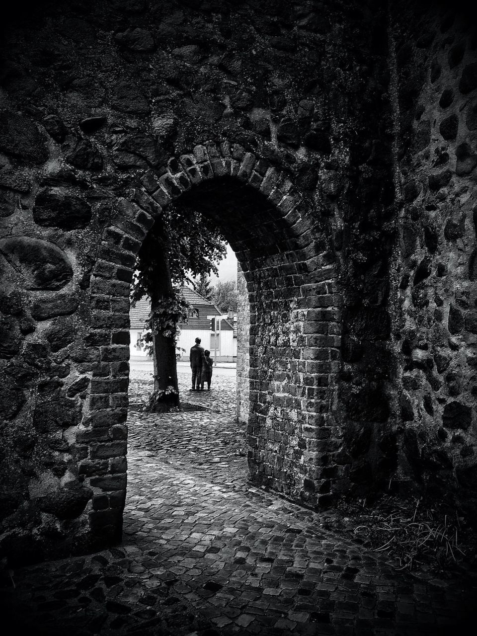 arch, indoors, architecture, built structure, tunnel, lifestyles, men, archway, full length, leisure activity, stone wall, wall - building feature, walking, rear view, person, silhouette, standing