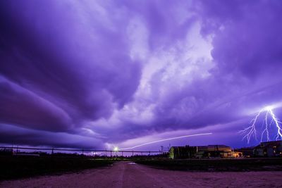 Panoramic view of illuminated city against dramatic sky