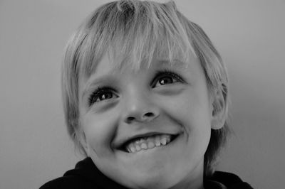 Close-up of cute smiling boy looking away against wall