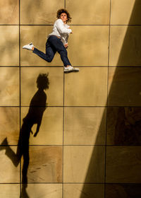 Low angle view of man jumping against wall with shadow