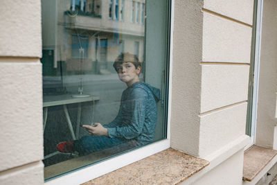 Thoughtful boy sitting by window