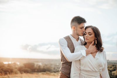 Young couple kissing against sky