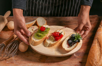 Midsection of man holding fruits on cutting board