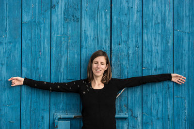 Smiling young woman standing against blue wall