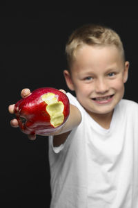 Portrait of smiling boy against black background