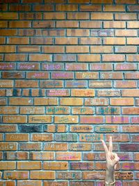 Low angle view of human hand on brick wall