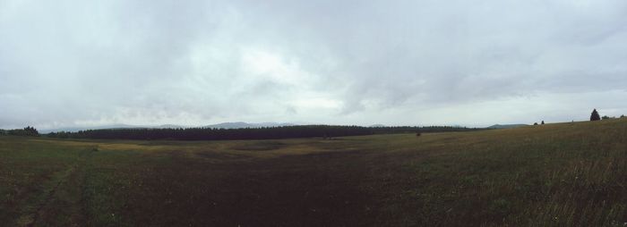 Scenic view of grassy field against cloudy sky