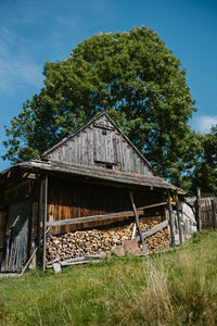 Abandoned building by trees on field against sky