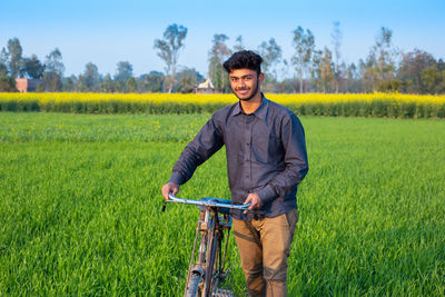 Portrait of young man riding bicycle on field