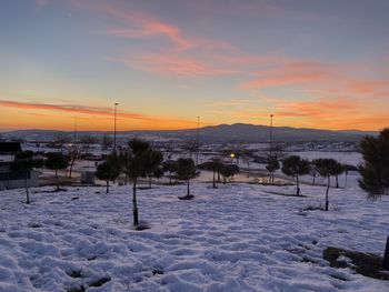 Scenic view of snow covered field against sky during sunset