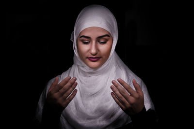 Close-up of woman burka praying in darkroom