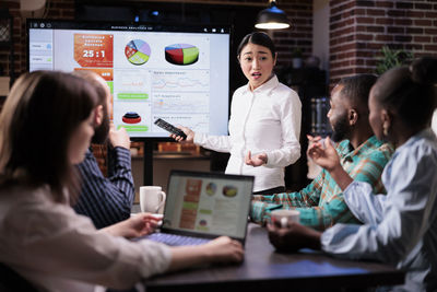 Businesswoman discussing with colleague at desk in office