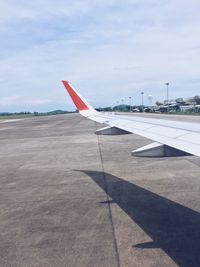 Airplane flying over airport runway against sky