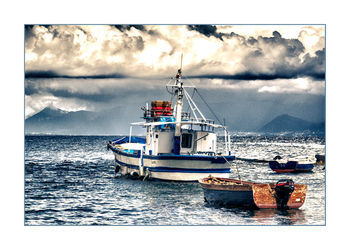 Boats in sea against cloudy sky