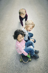 High angle view of children enjoying while sitting on skateboard