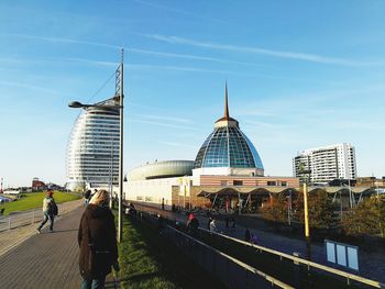 People walking on bridge in city against sky