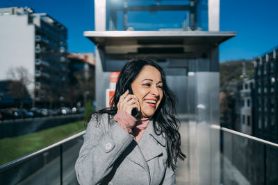 Smiling and happy executive brunette woman talking on the mobile phone in the business center person