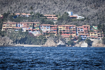 Houses by sea against buildings in city