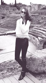 Portrait of woman standing by railing against old ruin