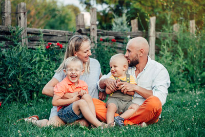 Friends sitting on grassland against plants