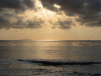 Warm sea sunset with sailing boat and gorgona island at the horizon . tuscany, italy