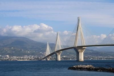 Bridge over calm sea against cloudy sky