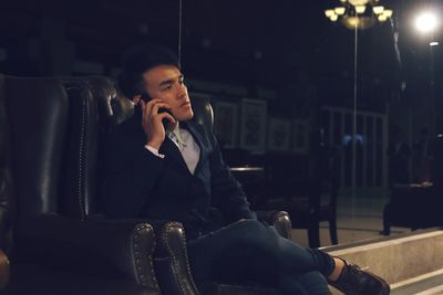 Young man using mobile phone while sitting on seat