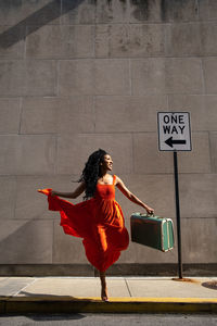 Smiling woman jumping with her suitcase 