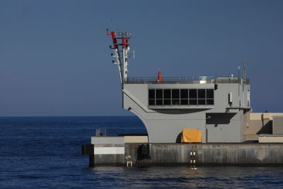 Built structure on pier in sea against clear sky