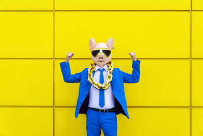 Full length portrait of a boy standing against yellow wall