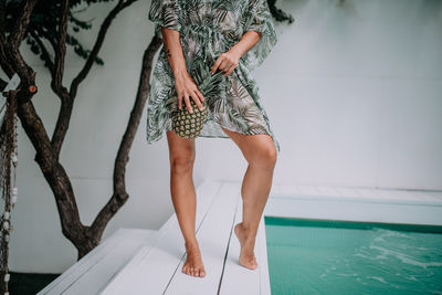 Low section of woman standing by swimming pool