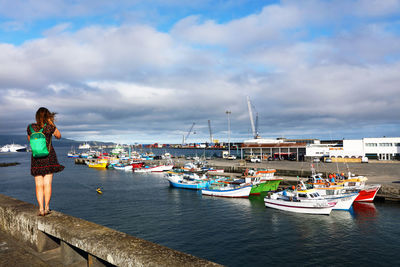 Woman standing at harbor against sky