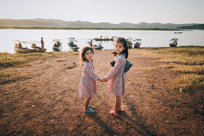 Children standing on field against sky