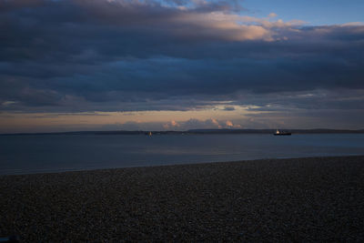 Scenic view of sea against dramatic sky at sunset