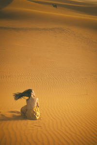 Woman in yellow dress playing with the wind in the desert iv