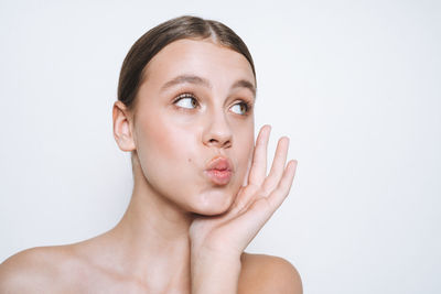 Beauty portrait of funny young girl with fresh skin tone showing kiss on white background