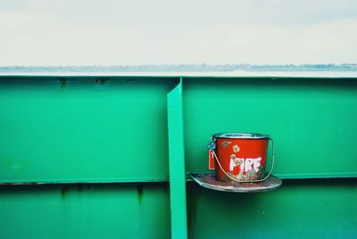 Bucket against green metallic wall
