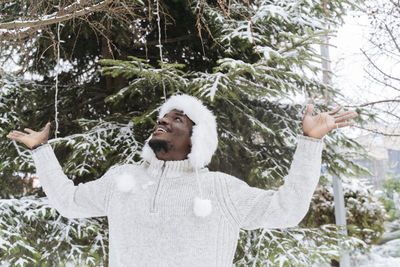 Happy man enjoying snow in front of tree